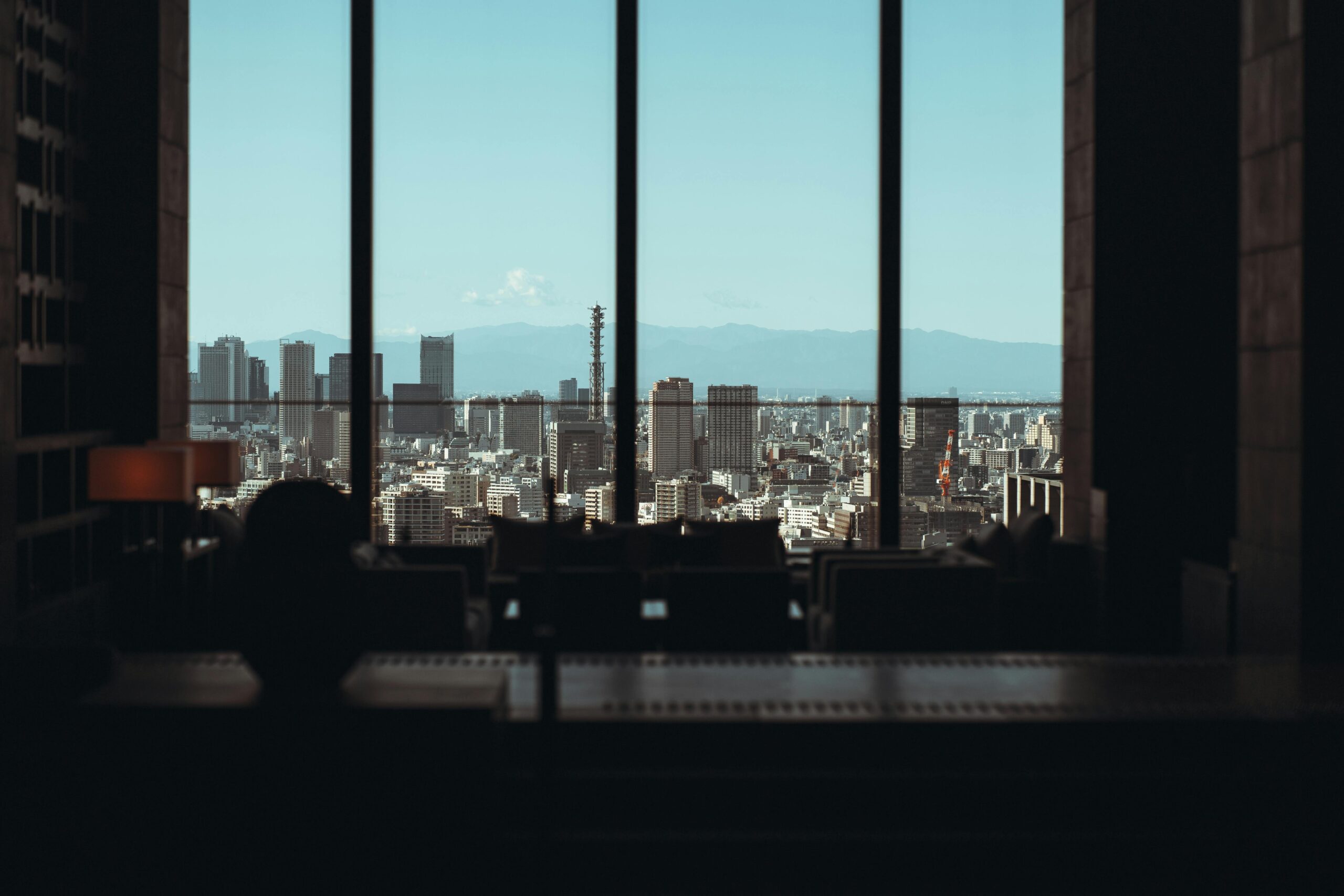 Dramatic Tokyo skyline view from a high-rise window with urban cityscape and blue skies.